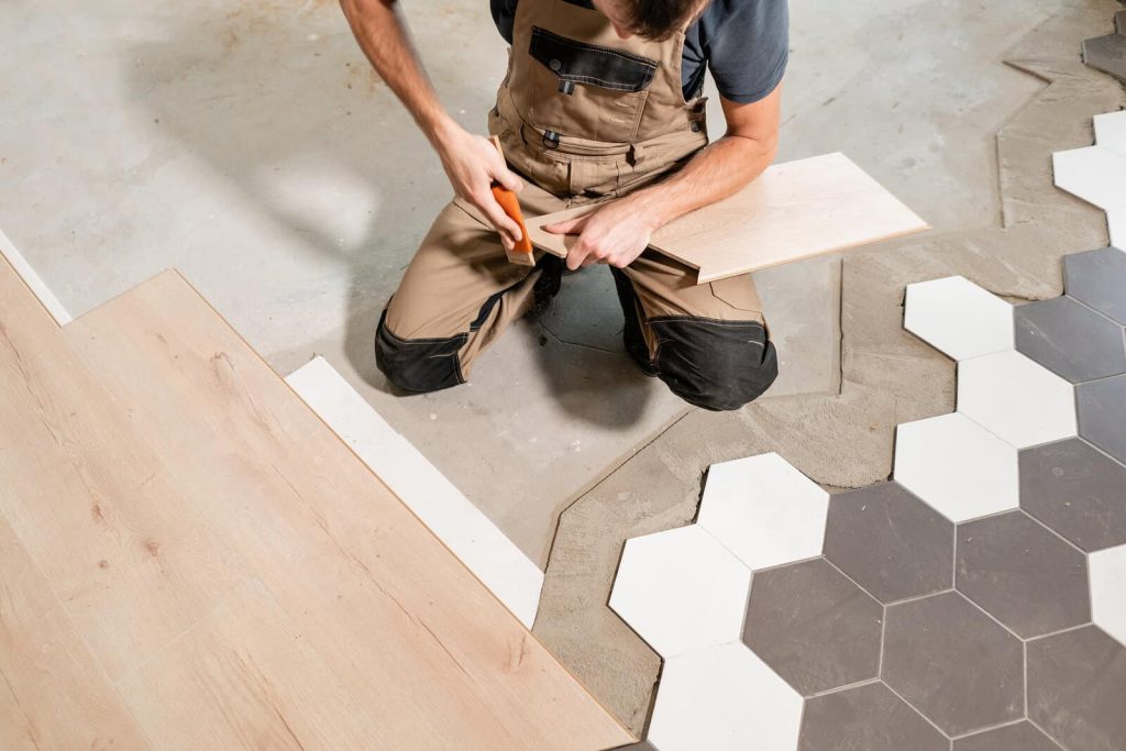 man on knees lays black and white bathroom tile