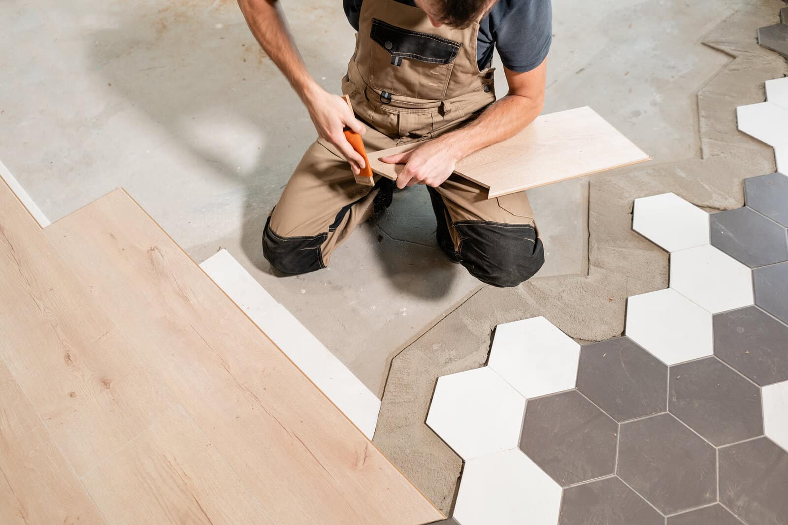 man on knees lays black and white bathroom tile