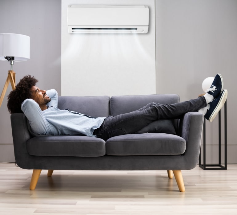 Man relaxing on couch enjoying cool indoor AC comfort