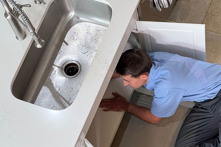 Plumber working under sink for plumbing inspection
