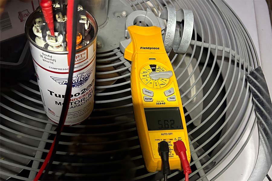 HVAC technician testing AC capacitor
