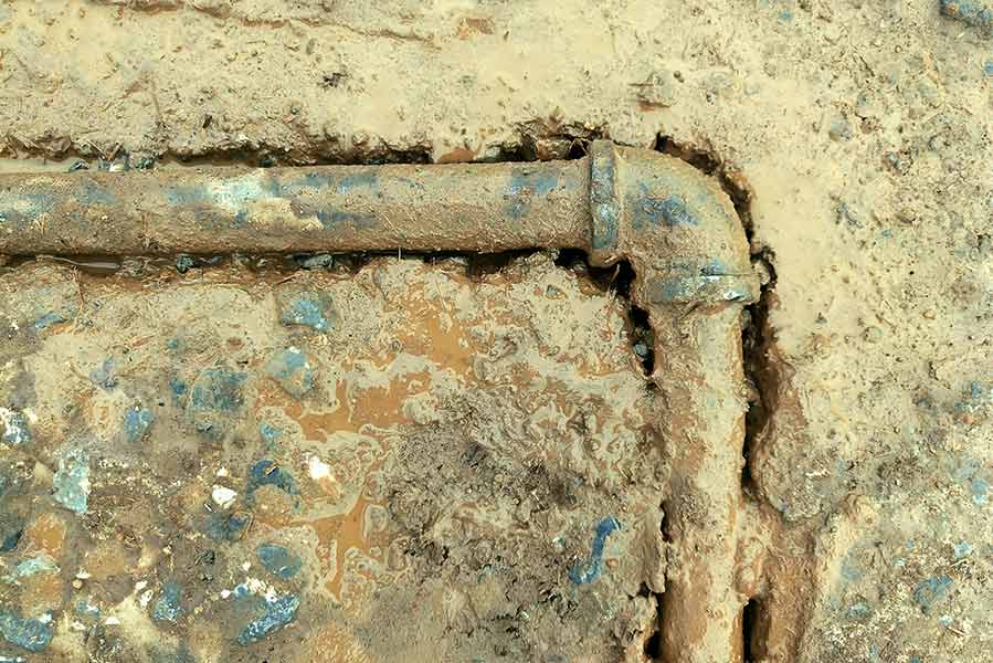 Rust-damaged pipe exposed during slab leak repair