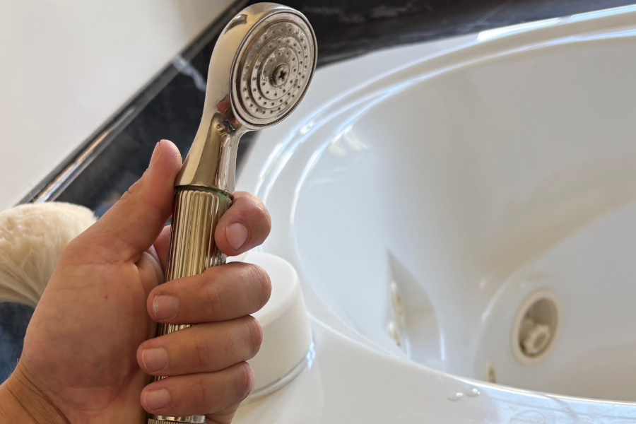 Handheld shower attachment installed on a master bathroom jetted tub, positioned for convenience and easy rinsing.