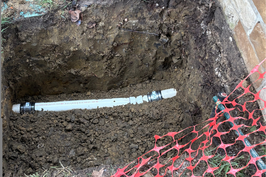 Dedicated plumbing technician in a trench to complete a challenging sewer line repair under slab in Frisco.