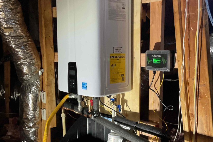Tankless water heater and whole-home descaler mounted in a home attic, with insulated water piping and secure wall installation.