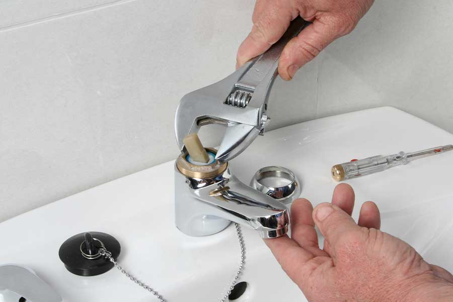 Emergency plumber repairing a leaking bathroom sink faucet in Lewisville TX
