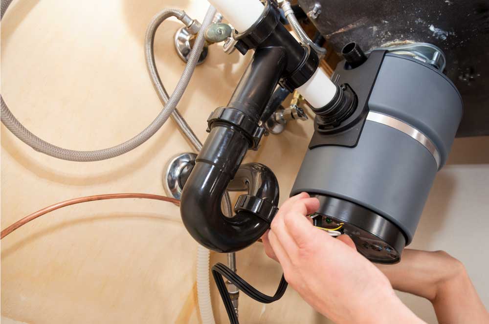 Garbage disposal repair being completed under kitchen sink in Coppell TX